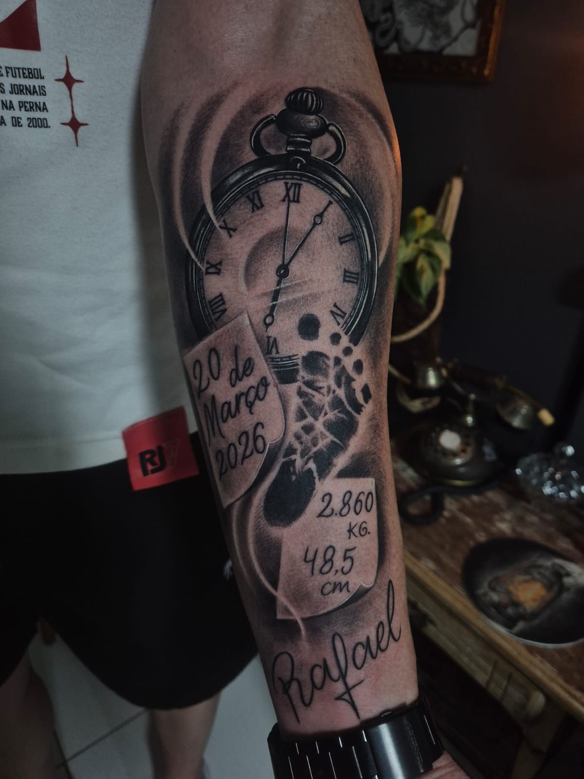 Tatuagem de relógio com pegada de bebê e nome Rafael
