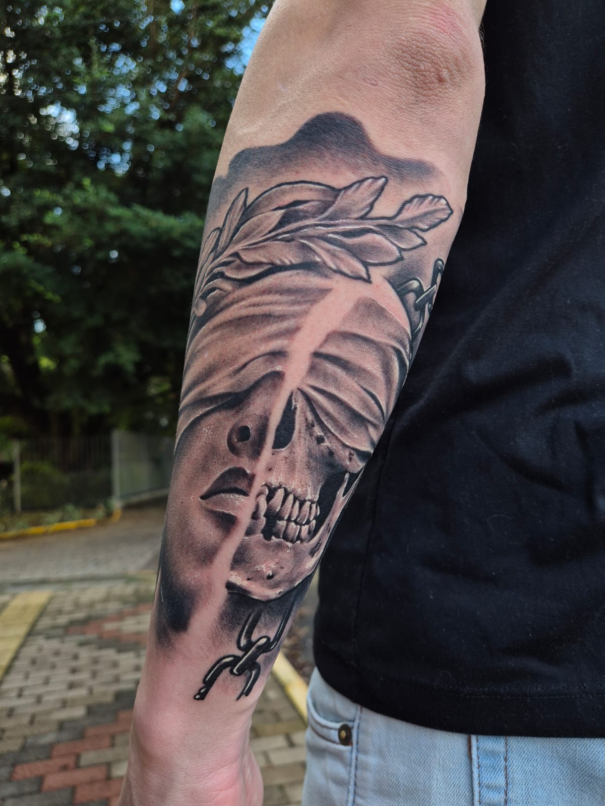 Tatuagem de caveira com louros no antebraço